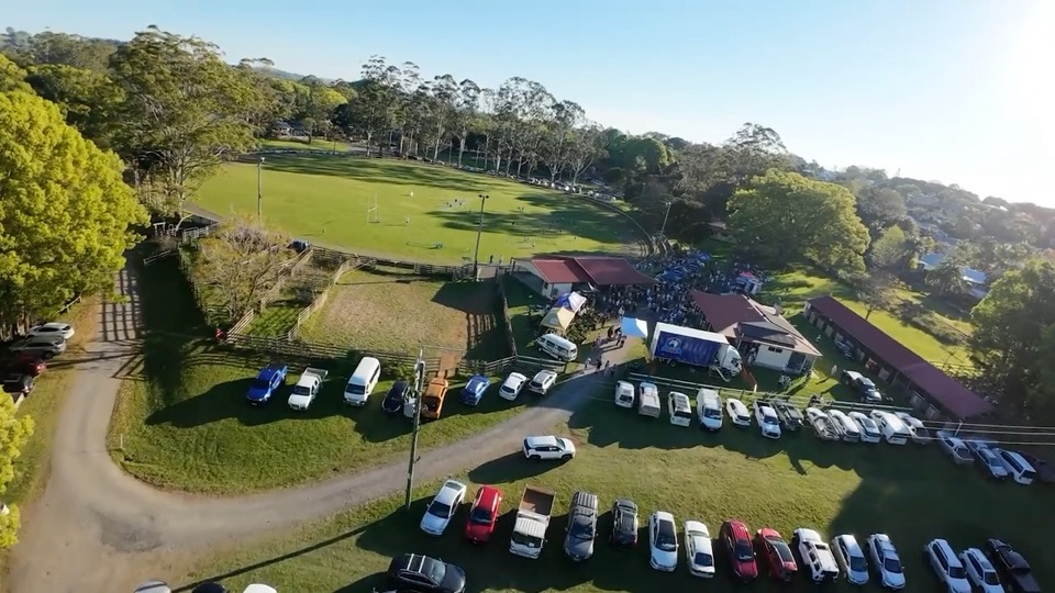 Aerial view of cars and a crowd gathered at the Bowlo grounds