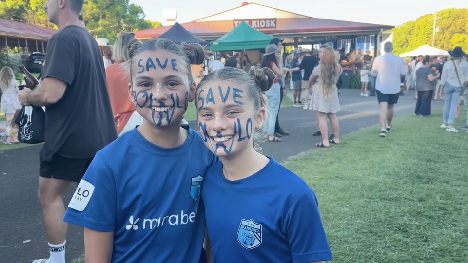 Two girls in sports tops with SAVE BOWLO painted on their faces