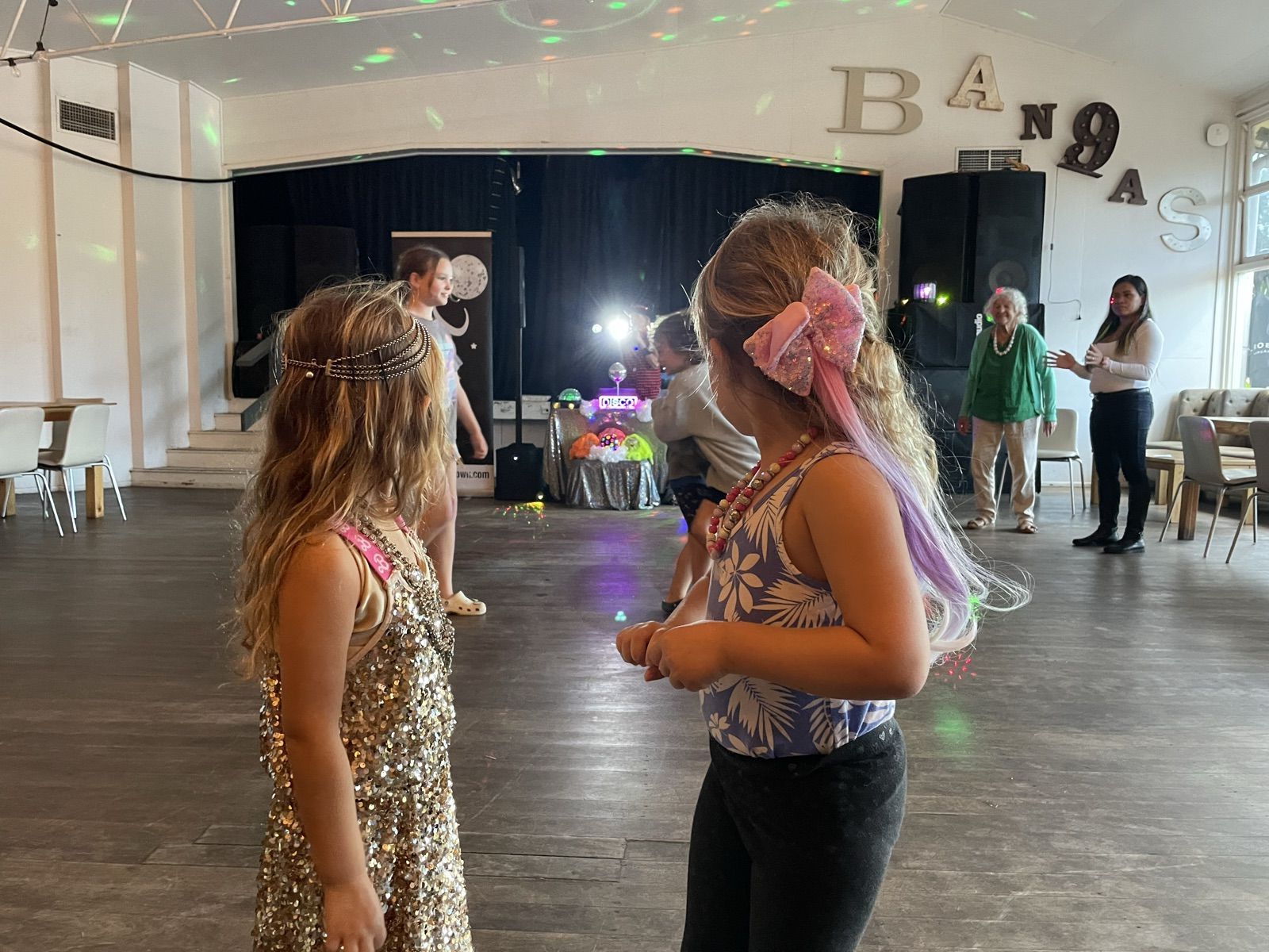 Kids dancing at a disco in the Bowlo's hall, with grown-ups looking on